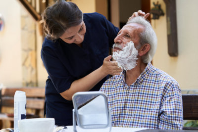 a nurse helping a senior shave