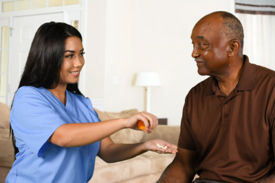 a healthcare worker helping a senior take his pills